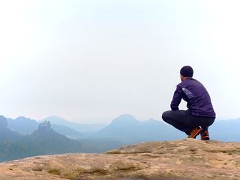 Rear view of man on rock against sky