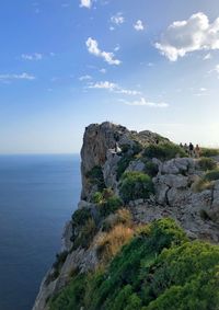 Cliff by sea against sky