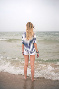 Rear view of young woman standing on beach