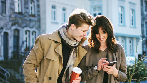 Friends standing on mobile phone in city