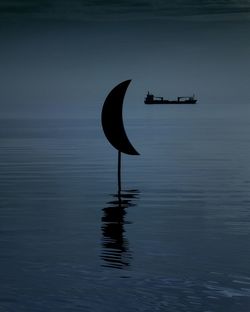 Silhouette boat in sea against sky at dusk