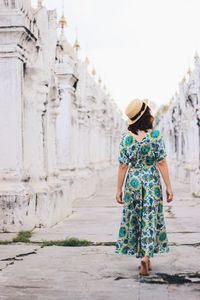 Rear view of woman with umbrella standing against built structure