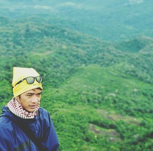 High angle view of young man wearing jacket on grassy mountain