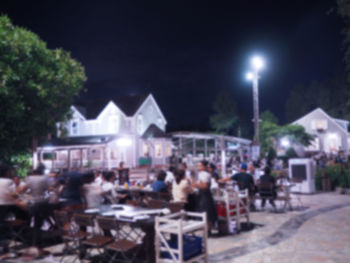 Illuminated street by buildings in city at night