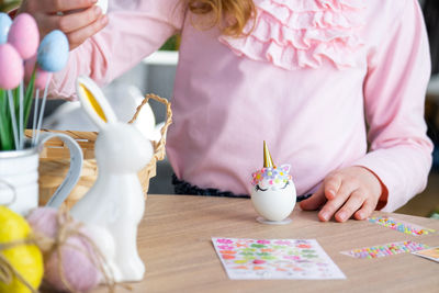 Midsection of girl playing with gingerbread house at home