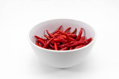 Close-up of red chili peppers in bowl against white background