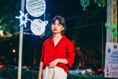 Young woman looking away while standing outdoors