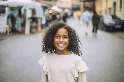 Portrait of smiling girl with curly hair at amusement park