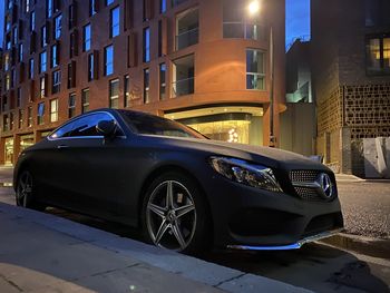 Car on street against illuminated buildings in city