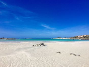 Scenic view of beach against blue sky