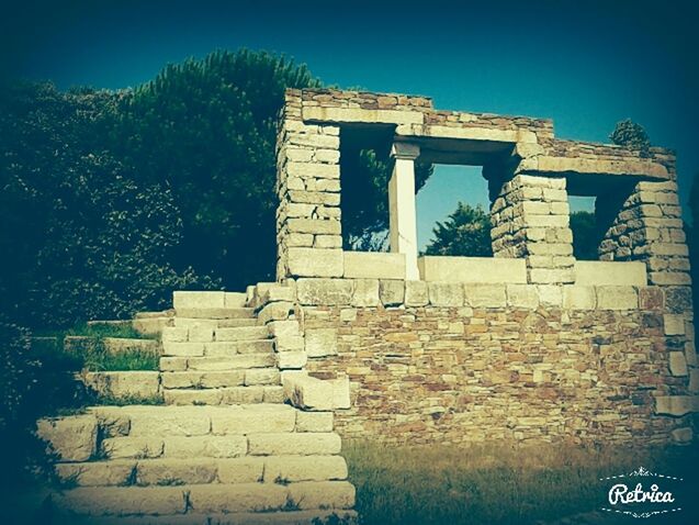 architecture, built structure, building exterior, clear sky, stone wall, blue, low angle view, old, history, wall - building feature, day, old ruin, the past, text, sky, sunlight, abandoned, outdoors, damaged, stone material