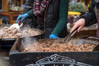 Vendors cooking duck confit at market stall