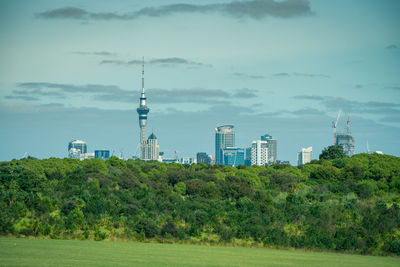 Trees and buildings against cloudy sky