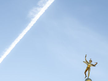 Low angle view of airplane flying against blue sky