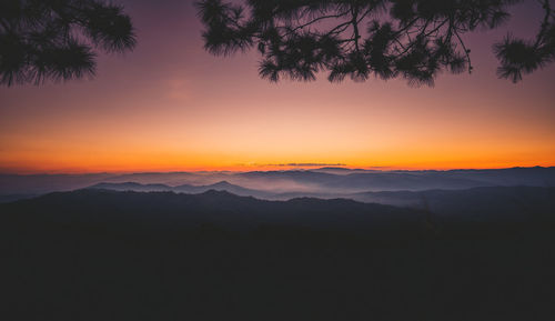 Scenic view of silhouette mountains against orange sky