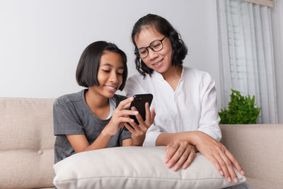 Happy young woman looking away while sitting on sofa