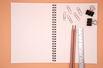 Directly above of blank diary with office supply on brown background