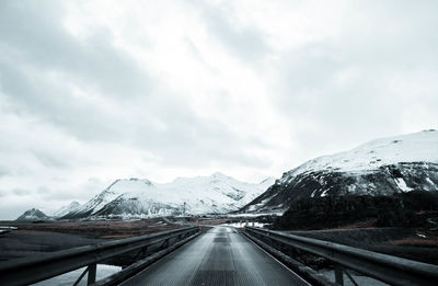 Road leading towards snowcapped mountains against sky