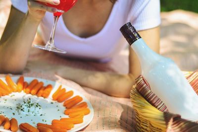 Midsection of woman holding wineglass with sausages and dipping sauce in foreground