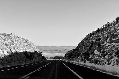 Road leading towards mountains against clear sky