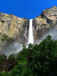 Scenic view of bridalveil falls in yosemite valley against blue sky