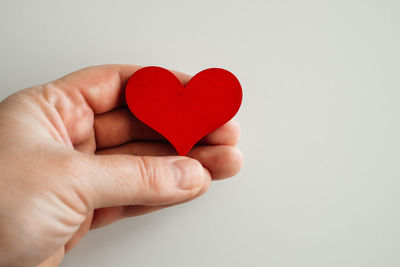 Close-up of hand holding heart shape over white background