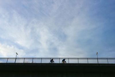 People on bridge against sky in city