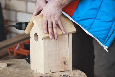 A man puts a roof on a birdhouse. hands close up. diy concept. the process of the carpenter.