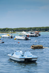 Boats moored on sea against clear blue sky