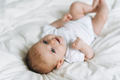 Cute baby girl 2-4 month on the bed with white linen, natural tones, selective focus