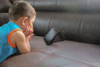 Boy lying down while sitting on floor at home