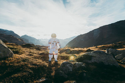 Rear view of man on rock against sky