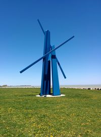 Traditional windmill on field against clear blue sky