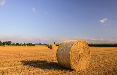 Hay bales on field against sky