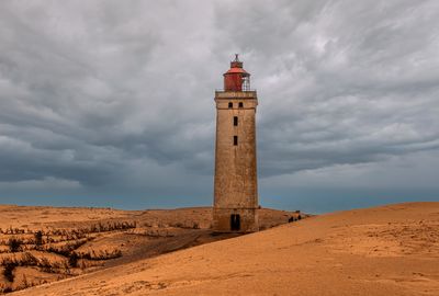 Lighthouse on beach against sky