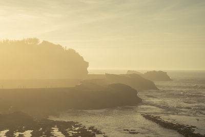 Rock formation on beach against sky during sunset