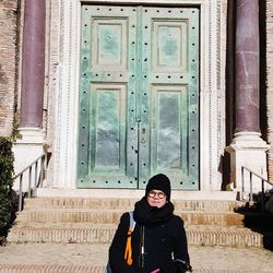 Portrait of smiling woman standing against door