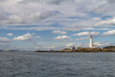 Lighthouse on sea against buildings