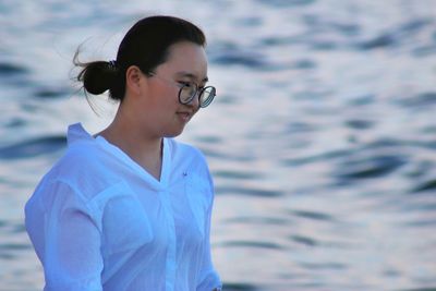 Smiling woman wearing eyeglasses against sea