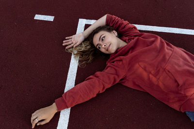 High angle view of smiling young woman lying on sports track