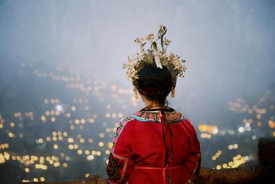 Rear view of young woman in traditional clothing standing against sky