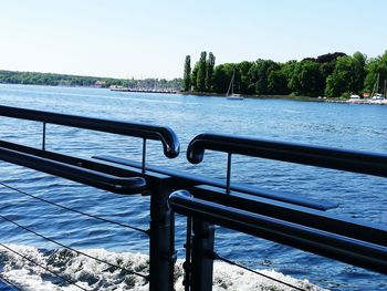 Railing sailing in river against clear blue sky