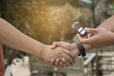 Cropped hand giving car lock to friend