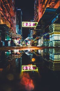 Illuminated street amidst buildings in city at night