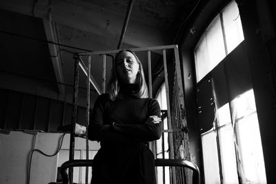 Portrait of woman standing against window