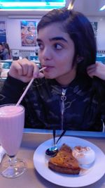 Close-up of young woman with drink on table