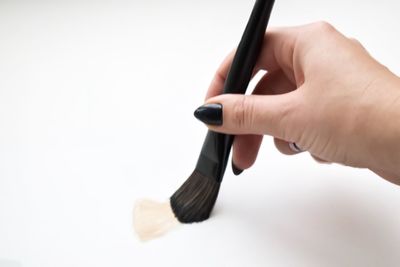 Close-up of hand holding pen against white background