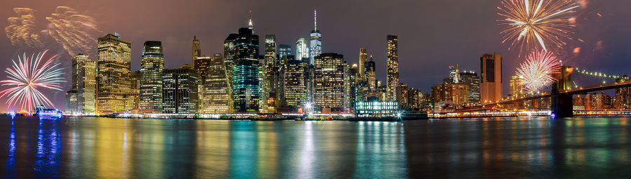 Panoramic view of illuminated cityscape and river at night