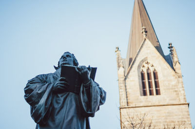 Low angle view of statue against temple against clear sky