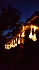 Low angle view of illuminated light bulb against sky at night